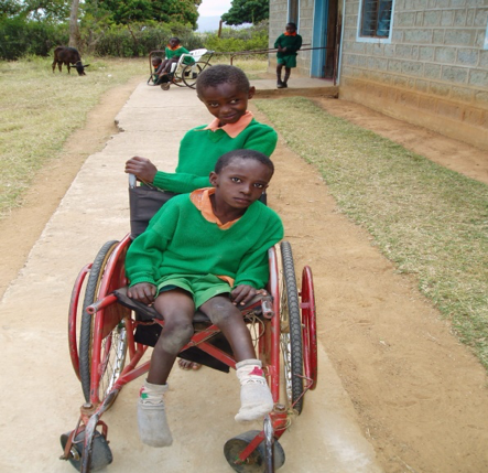 a child pushing another child in a wheelchair