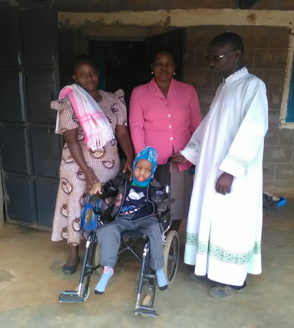 A child in a wheelchair in the centre and three adults behind him